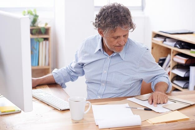 A person is sitting at a desk, looking stressed and overwhelmed by paperwork related to their disability claim. The desk is cluttered with medical bills and forms.