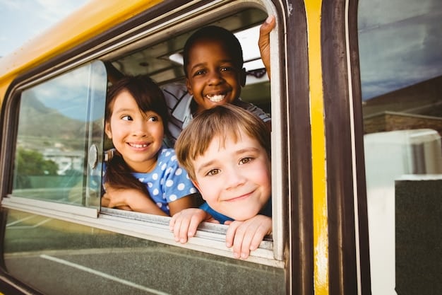 Students of various ages sitting inside a school bus, smiling and looking at the camera.