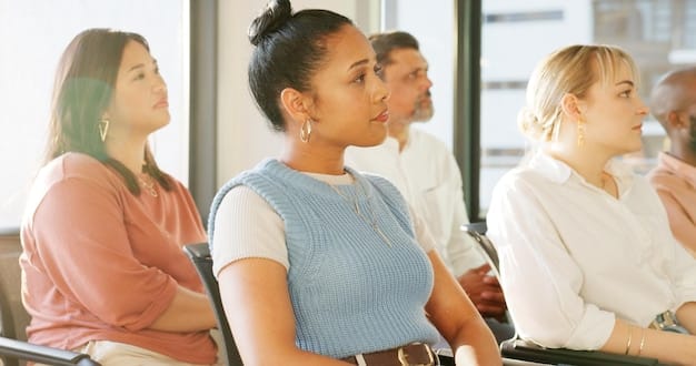 A group of diverse volunteers attentively listening to a speaker during a training session on new compliance regulations for non-profit organizations.