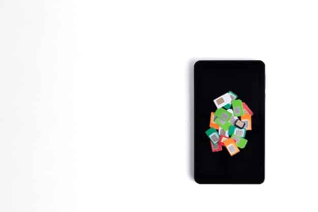 A top-down view of a recycling bin filled with various electronic devices, such as phones, laptops, and tablets. The bin is labeled with a recycling symbol and is placed against a bright, neutral background.