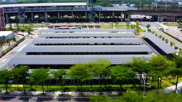 A medium-sized business facility with solar panels installed on the roof, surrounded by green spaces and trees. Show electric vehicle charging stations in the parking lot.