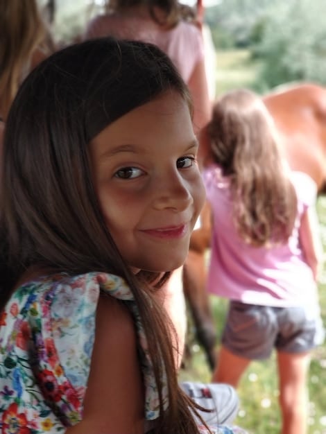 A close-up shot of a Brazilian volunteer teaching English to a group of children in a rural village, with smiles and engagement visible on their faces.
