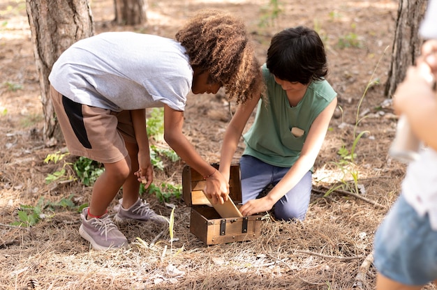 A group of children and adults working together to build a fence around newly planted trees in a reforestation project, showing community involvement and teamwork.