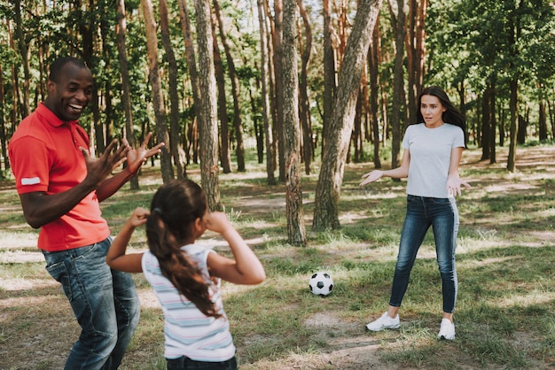 Volunteers coaching a group of children playing soccer in a community field.