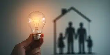 Mão segurando uma lâmpada acesa, simbolizando economia de energia para famílias de baixa renda.